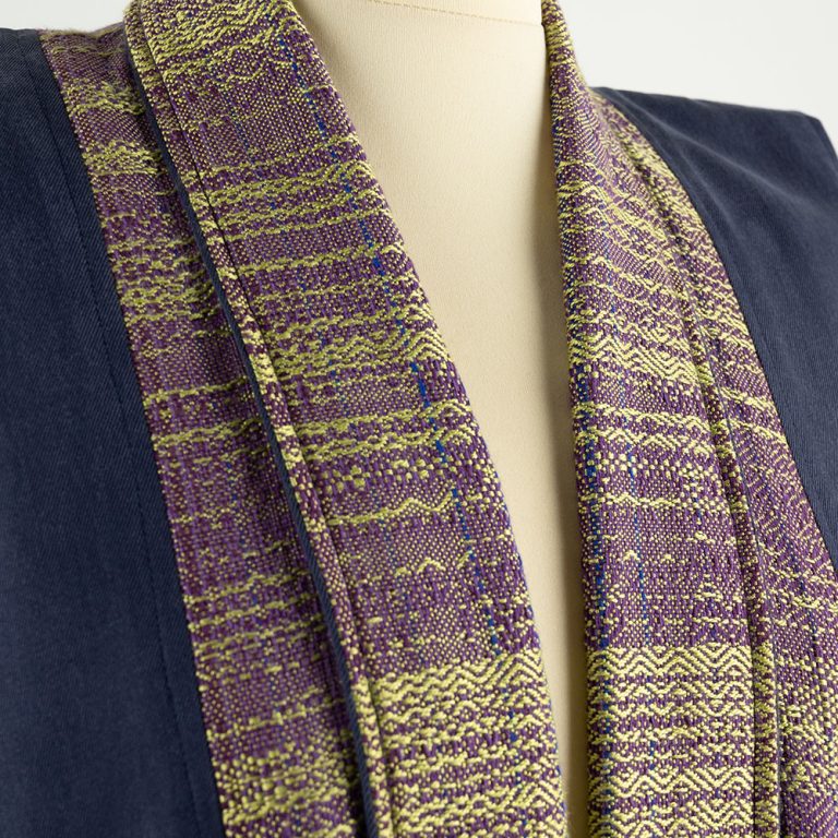 Close up of the neckline of a coat. The fabric is a complex weave in burgundy and gold.