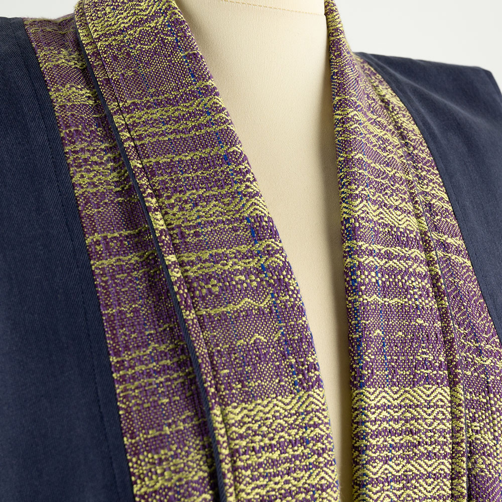 Close up of the neckline of a coat. The fabric is a complex weave in burgundy and gold.